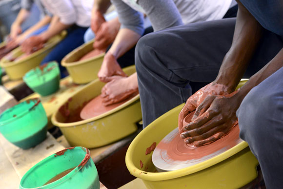 Mamadou N'Diaye, right, sculpts clay at a Mesh Baltimore pottery class.